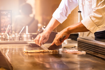 The chef cooks fresh, fast food according to the orders of customers in the Japanese teppanyaki...