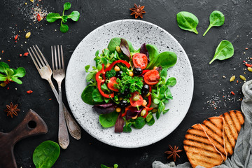 Vegetable salad with spinach, tomatoes, paprika and pumpkin seeds in a plate on a wooden background Top view. Free space for your text. Flat lay