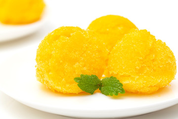 Fototapeta na wymiar Mango sorbet, summer dessert decorated with mint leaves. Closeup of a bowl of mango sorbet. 