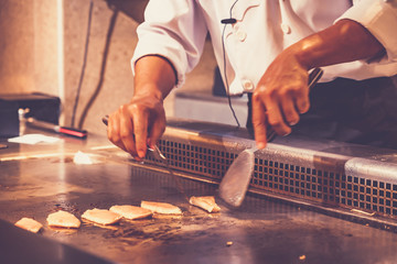 The chef cooks fresh, fast food according to the orders of customers in the Japanese teppanyaki restaurant.