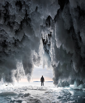 Silhouette of a man in a cave covered with blue ice and icicles