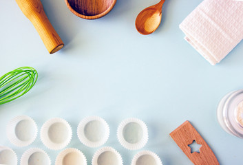 Culinary background. Cooking utensils, a whisk, a rolling pin, cupcake pans, a wooden bowl and baking ingredients. Bakery background frame. Top view, copy space.