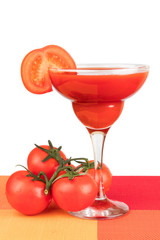 A glass with tomato juice with a slice of tomato on white isolated background