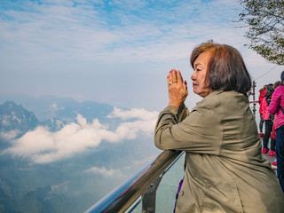 Beautiful Senior asian women stand on Tianmen mountain Glass balcony with winning Pose and beautfiul View on the mountain at zhangjiajie city china