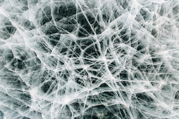 Texture of frozen ice with cracks, frozen like a cobweb. Baikal, Russia