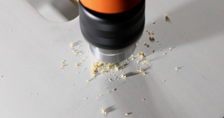 Closeup of a drill bit drilling a hole in a wooden plank