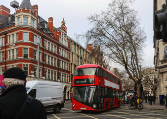 Busy London intersection on overcast wet winter day with people on bikes and double decker bus on...