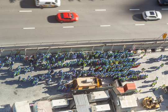 Arial View Of A Big Group Of Construction Workers, Grouped On Side Of The Road During A Fire Drill