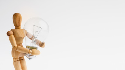 Wooden mannequin figure holding lamp bulb on white