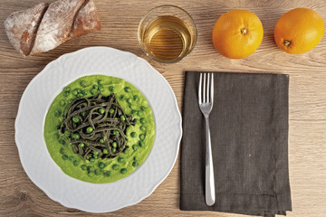 pasta al nero di seppia con salsa di piselli dall'alto piatto tondo