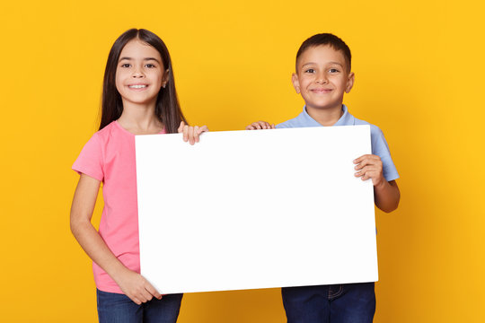 Boy and girl holding empty board for advertisement