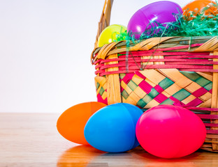 Easter basket with colorful plastic Easter eggs. Vintage woven wicker egg hunt basket, green grass, and vibrant colored classic eggs.