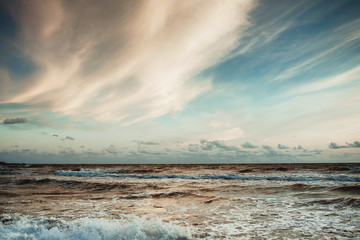 Obraz premium Beautiful sunset over wavy Baltic sea. Soft blue color and white yellow clouds on the sky.