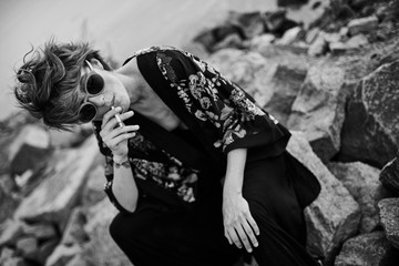 Black and white street photo of young woman smoking cigarette