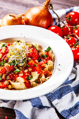 Pasta with tomato sauce and vegetables on wooden table
