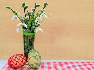 Easter composition with snowdrops, willow twigs and eggs with crocheted cover