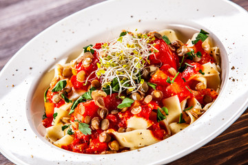 Pasta with tomato sauce and vegetables on wooden table