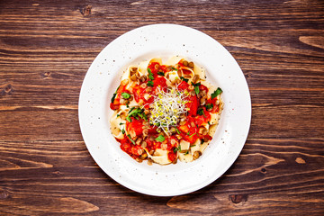 Pasta with tomato sauce and vegetables on wooden table