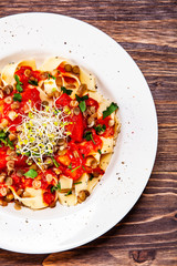 Pasta with tomato sauce and vegetables on wooden table