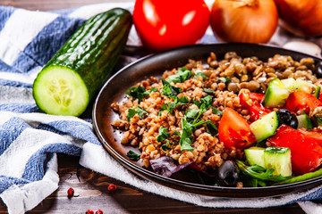 Groats with lentils and vegetables on wooden table