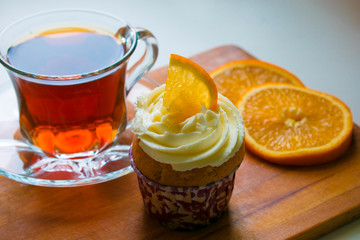 a glass cup of tea, a cupcake with orange slices on a wooden tray. Healthy food. tea party