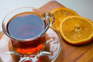 glass cup of tea with orange slices on a wooden tray