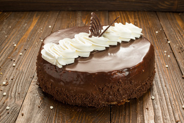 Dark chocolate vegan cake with candies and nuts on wooden background