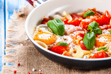 Shakshuka - fried eggs with vegetables in frying pan