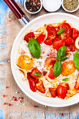Shakshuka - fried eggs with vegetables in frying pan