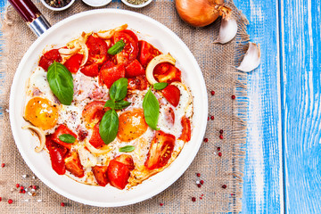 Shakshuka - fried eggs with vegetables in frying pan