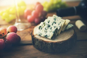 Foto op Plexiglas dor blue cheese on wood log slice with grapes and wine bottle © ronstik
