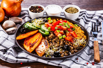 Groats with lentils and vegetables on wooden table