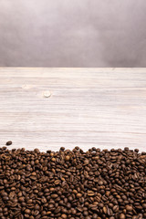 Roasted coffee beans in bulk on a light wooden background. dark cofee roasted grain flavor aroma...