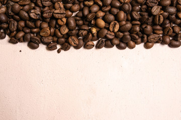 Roasted coffee beans in bulk on a light pink background. dark cofee roasted grain flavor aroma cafe, natural coffe shop background, top view from above, copy space
