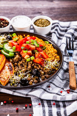 Groats with lentils and vegetables on wooden table