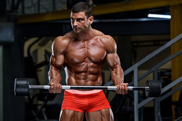 Fototapeta na wymiar Muscular Man Lifting Weights at the Gym