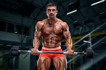 Fototapeta na wymiar Muscular Man Lifting Weights at the Gym