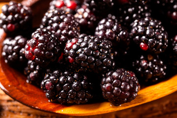 fresh blackberries in wood bowl on wooden table. Selective focus.