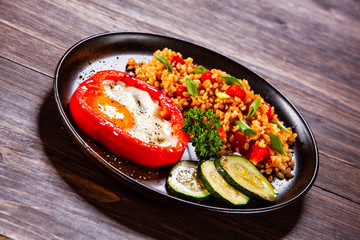 Fried egg, groats and vegetables on wooden table