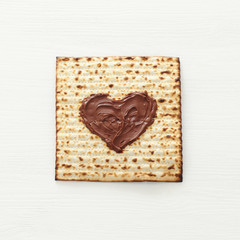 Pesah celebration concept (jewish Passover holiday) with chocolate heart over matzah. Top view flat lay
