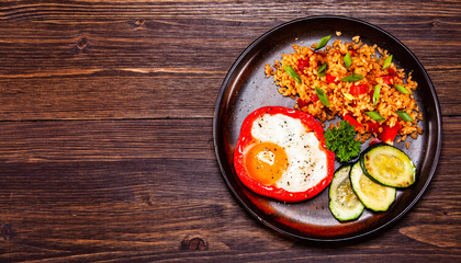 Fried egg, groats and vegetables on wooden table