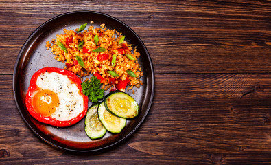 Fried egg, groats and vegetables on wooden table