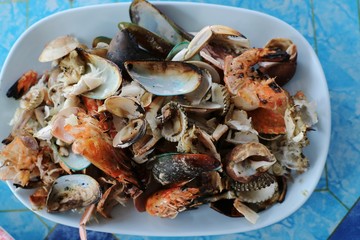 Shells, shrimp shells, and crab shells on white plate in seafood restaurant. Waste food concept.