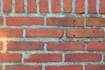 Naklejka premium Red brick wall with grey mortar and plug holes
