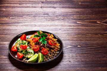 Groats with lentils and vegetables on wooden table