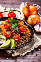 Groats with lentils and vegetables on wooden table