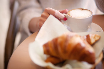 girl holding a coffee mug in the foreground croissants