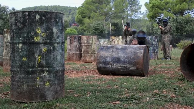Paintball players aiming and shooting with guns at opposing team outdoors 