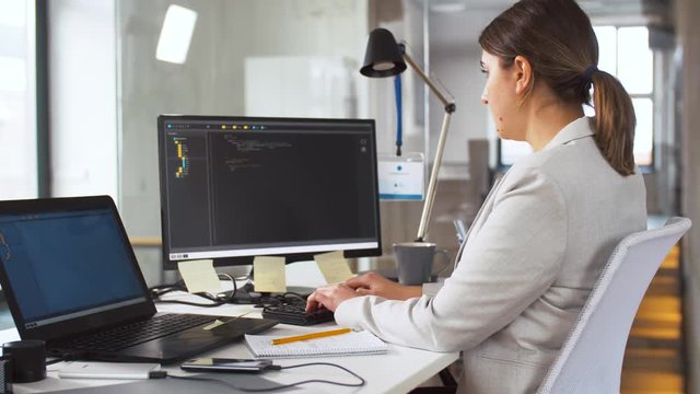 business, programming and technology concept - female programmer with script on computer screen working at office