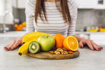Assortment of fruits on wooden table in front of young woman